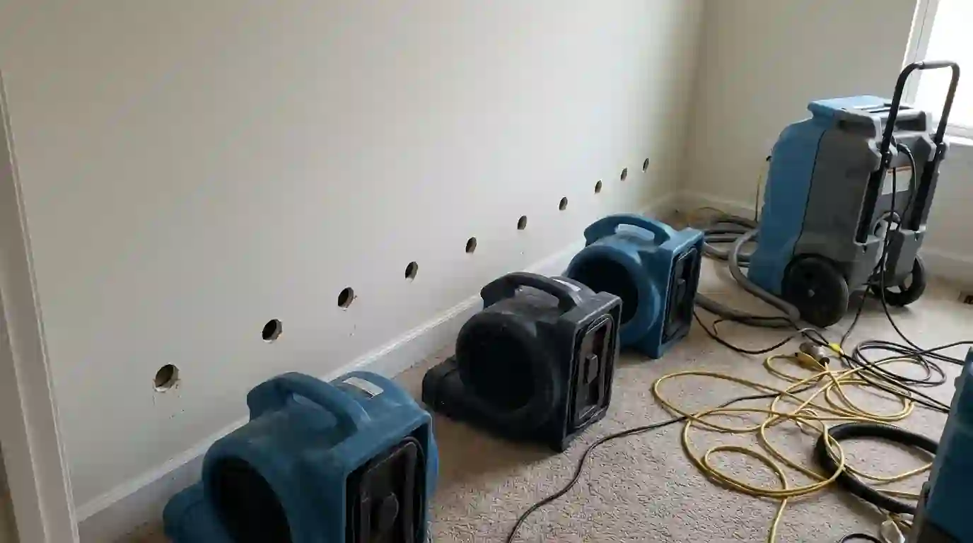Air movers drying the base of a wall